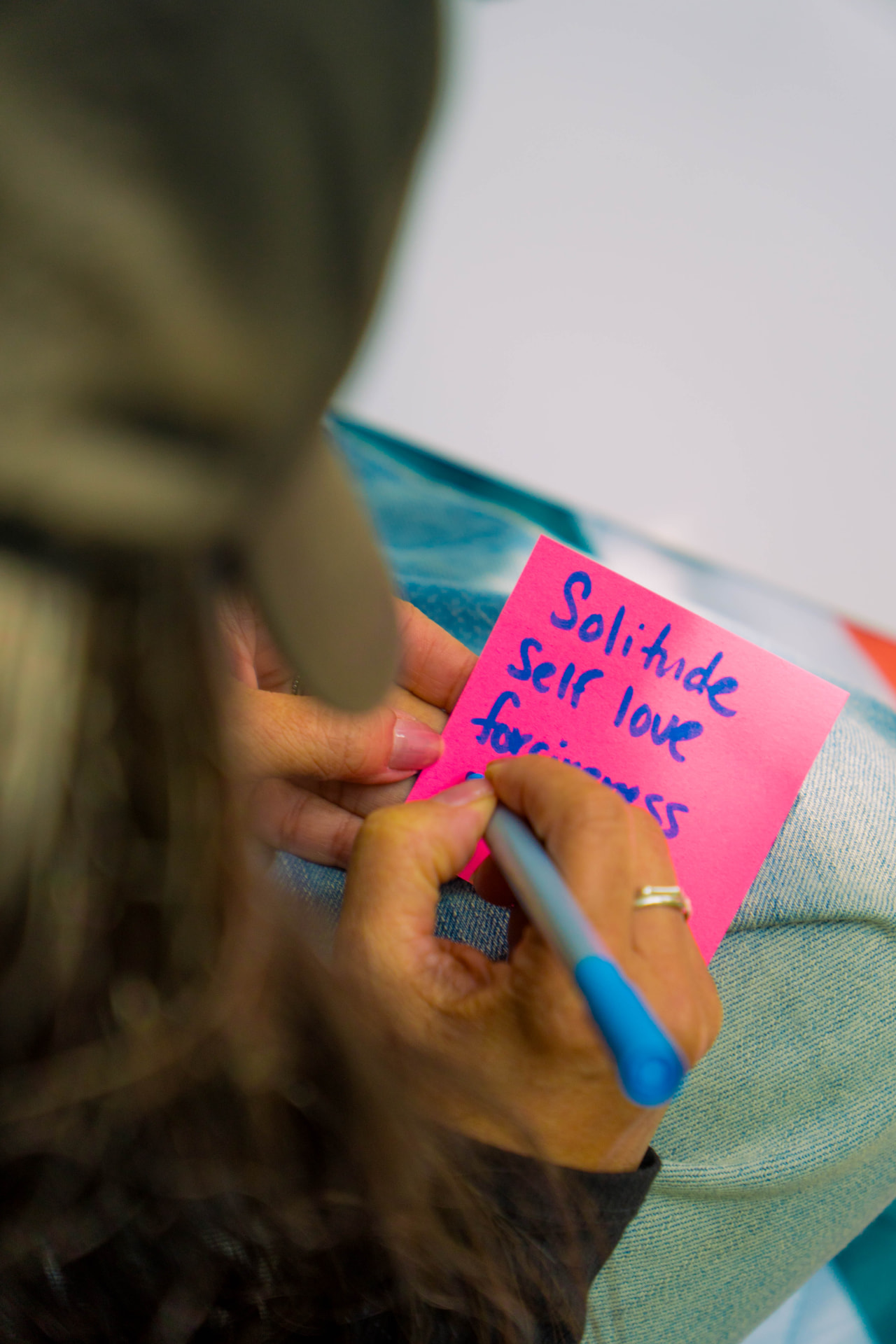 Writing 'solitude, self love, forgiveness' on a sticky note